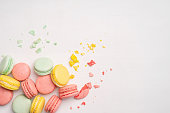 Pink, yellow and turquoise macaroons with crumbs and bitten bits on a white background. Background with traditional french dessert.