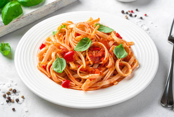 istock Italian traditional linguini pasta with tomatoes, pepper and basil on a light background. 1407713077