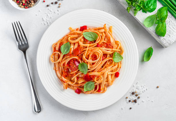 istock Italian pasta with tomatoes and basil on a light gray background. 1407713717