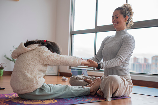Latina mother and daughter from Bogota Colombia, do Yoga at home while enjoying a very personal moment that brings them closer wearing comfortable clothes