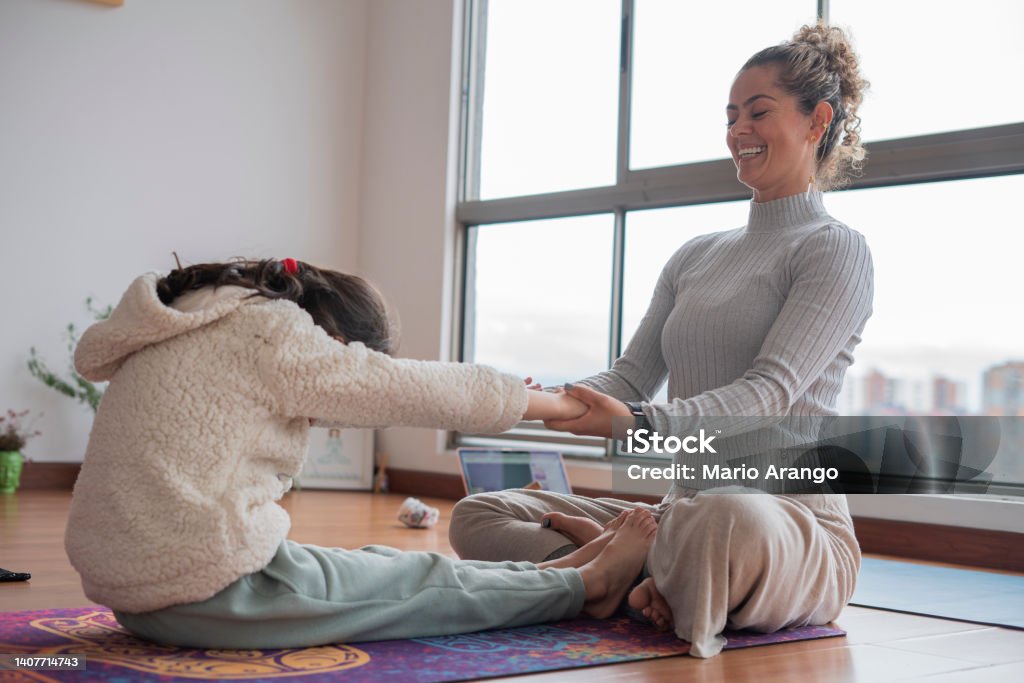 Mother and daughter do Yoga at home while enjoying a very personal moment that brings them closer Latina mother and daughter from Bogota Colombia, do Yoga at home while enjoying a very personal moment that brings them closer wearing comfortable clothes Latin America Stock Photo