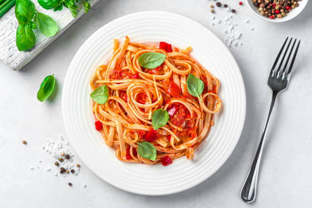 istock Classic linguini pasta with tomatoes and fresh basil on a light gray background. 1407714924