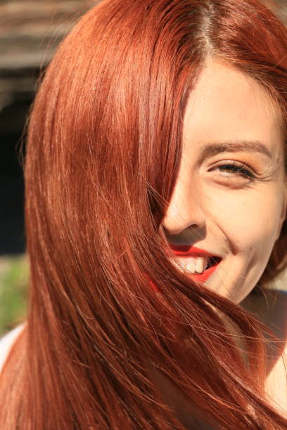 A Mexican model closeup of her dyed red hair over half of her face.