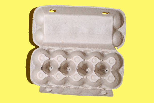 top view of Mockup or packaging design on a yellow background, empty paper box for eggs on a yellow background, eco friendly or green product. Open cardboard box with chicken eggs.