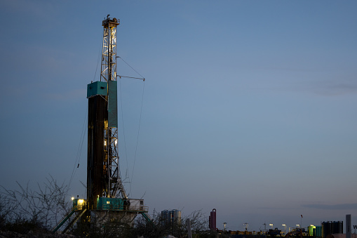 Fracking Drilling Rig Creating Gas or Oil Well Silhouetted at Dusk Under a Dramatic Sunset Sky