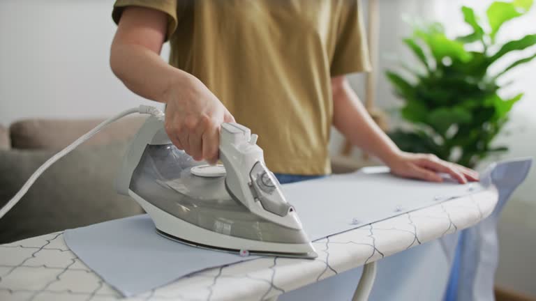 Woman ironing on ironing board at home