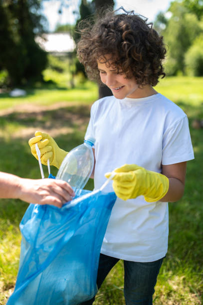 istock Someone helping a curly-haired teen to gather garbage 1407717373
