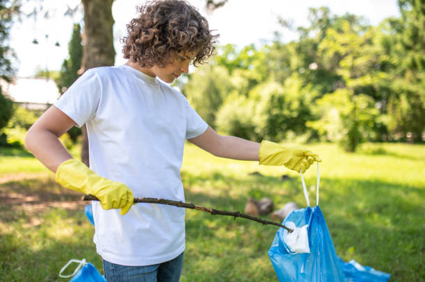 istock Cute young volunteer cleaning the park from plastic garbage 1407717374