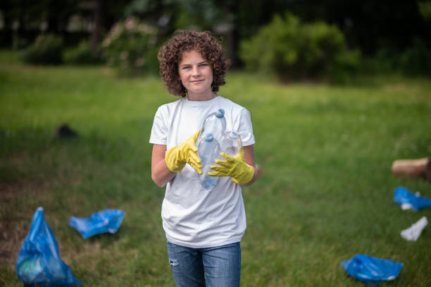 istock Kid in yellow gloves in the park gathering garbage 1407717440