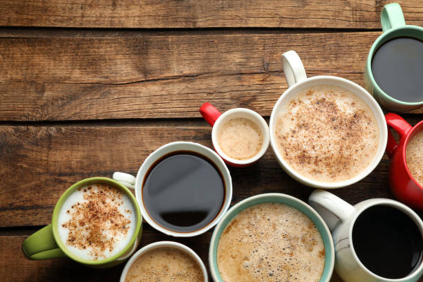 istock Many cups of different coffees on wooden table, flat lay. Space for text 1407720976