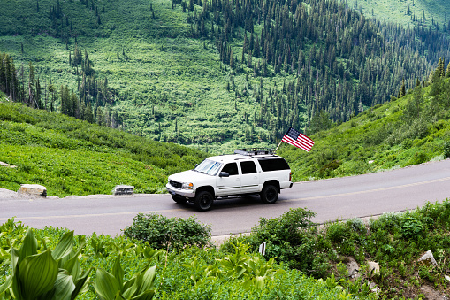 Glacier National Park, USA - July 4, 2016: Car with American flag on Going-to-the-Sun road on the 4th of July national holiday