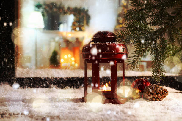 Snow falling onto window sill with Christmas lantern outdoors