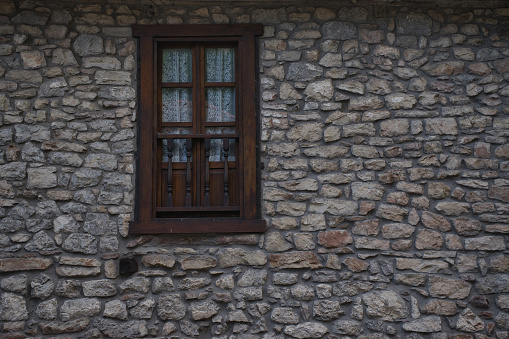 Natural stone facade with wooden window detail. Rural house in the Pyrenees. Copy space on the right side