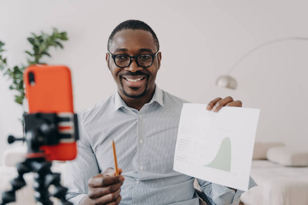 istock Afro freelancer has online brainstorm. Positive man shows data chart speaking at online conference. 1407723632