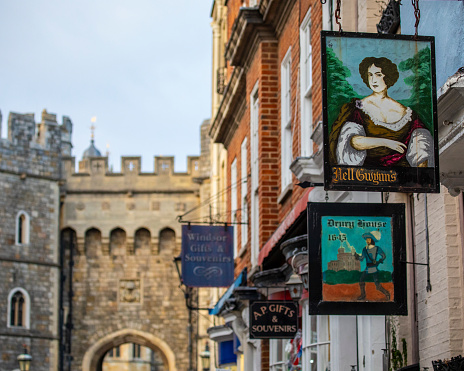 Windsor, UK - November 28th 2021: Vintage hanging signs on the exteriors of shops and tearooms in the historic town of Windsor, in Berkshire, UK.  Windsor Castle is in the background.