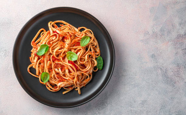 istock Italian linguini pasta with tomato sauce and fresh basil on a light background. 1407724644