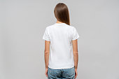Back view of woman in white t-shirt, isolated on gray background, template or mockup for logo