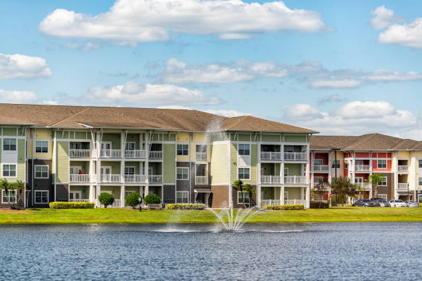 Orlando, Florida luxury lifestyle apartments buildings with three floors by lake water fountain in tropical city with blue sky clouds stock photo