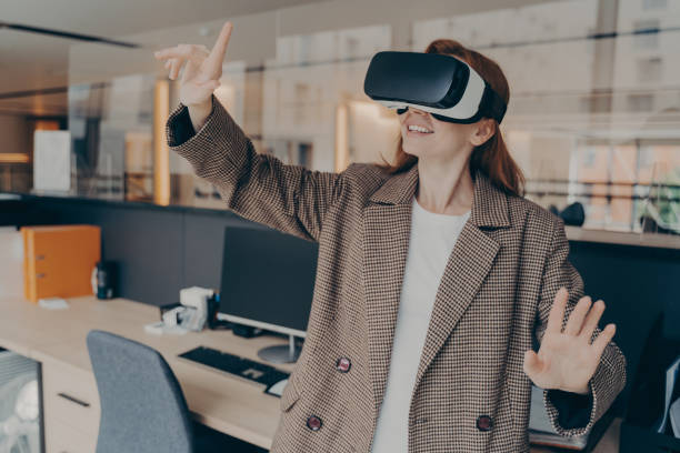 istock Happy female office worker in VR headset enjoying virtual reality game on her break 1407725896