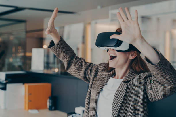istock Impressed red-haired business woman dressed wearing portable VR goggles exploring virtual world 1407725907