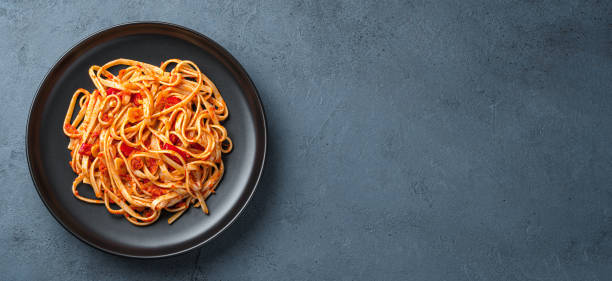 istock A portion of linguini pasta with tomatoes on a gray-blue background with a copy space. 1407727342