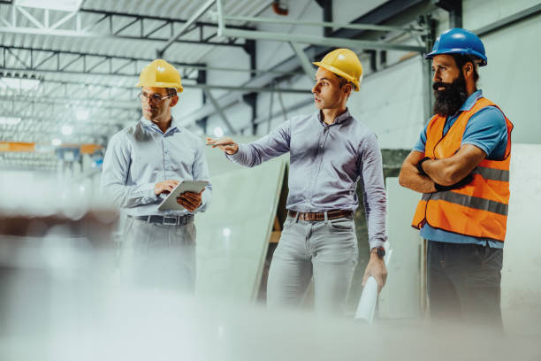 istock Employees and engineers in industry hall, discussing together 1407729600