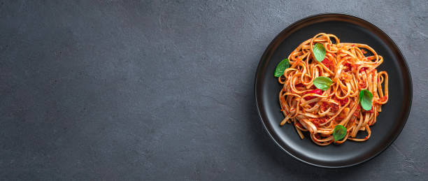 istock Pasta with tomato sauce and fresh basil on a dark background. 1407729785