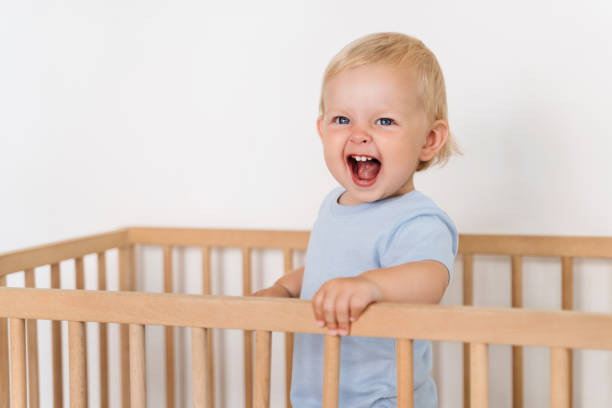 portret dziesięciomiesięcznego dziecka stojącego w łóżku, próbującego chodzić trzymając się zderzaków - one baby boy only zdjęcia i obrazy z banku zdjęć