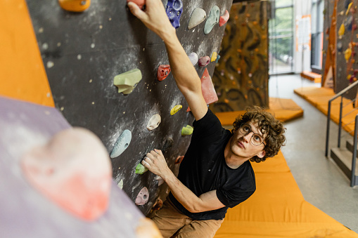 The man clambing on the bouldering wall indoor