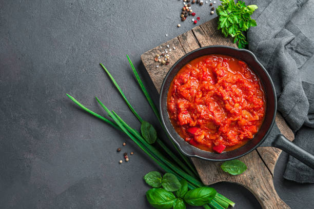 istock Homemade tomato sauce and fresh herbs on a dark background. 1407731025