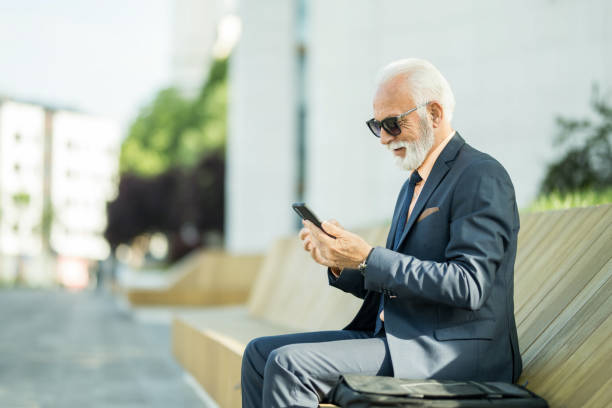 istock Senior businessman using phone outdoors in the city. 1407731803