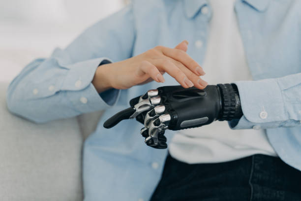 istock Girl is setting up her bionic hand and pressing buttons. Young woman with artificial arm at home. 1407731898