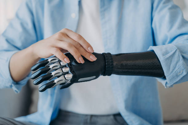 mano cibernética de la mujer amputada. la mujer discapacitada está cambiando la configuración de la prótesis robótica. - protesis fotografías e imágenes de stock