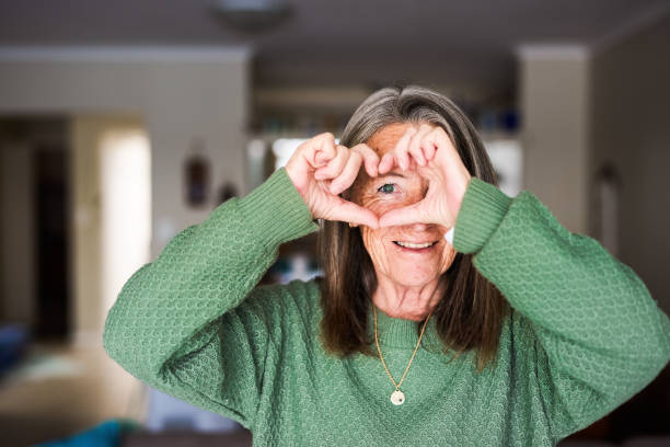 istock Smiling mature women with hands in a heart shape 1407731964