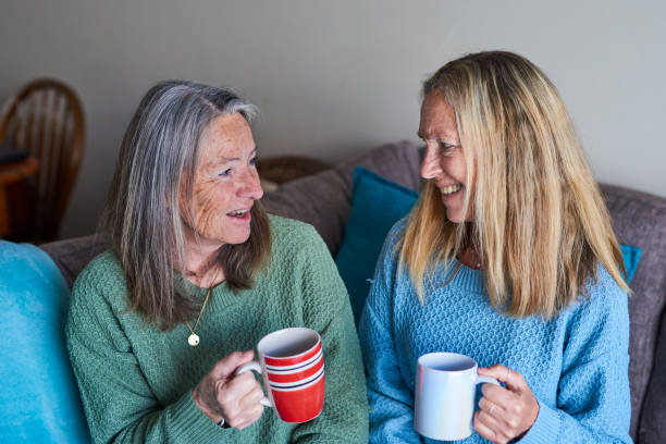 istock Smiling mature sisters drinking a cup of coffee together 1407731978