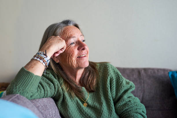 istock Smiling mature woman staring outwards while sitting on the couch 1407732005