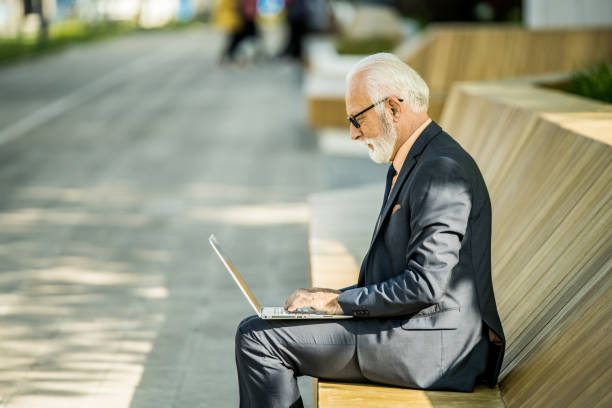 istock Senior businessman using laptop outdoors in the city. 1407732807