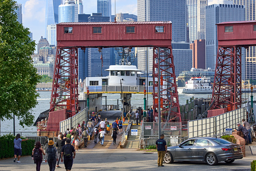 Governors Island, NY, USA - June 13, 2022: Visitors at Soissons Landing ferry dock at the north end of Governors Island. In the background is Lower Manhattan, a short ferry ride away.