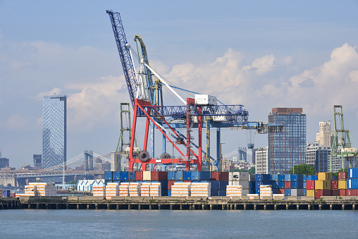 Brooklyn, NY - June 13, 2022: Gantry cranes of Red Hook Container Terminal in Red Hook, Brooklyn, NYC. In the background are tall buildings in Brooklyn Heights and Lower Manhattan.
