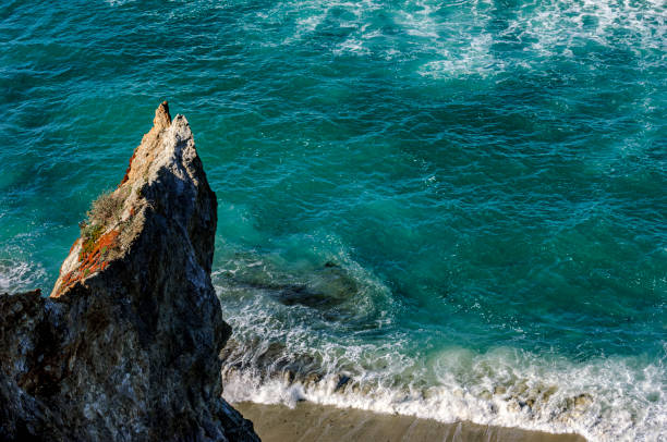 High angle view of beach along the rocky shore of the Big Sur coast.\n\nTaken at Taken from California Highway One, Big Sur, California, USA