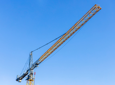 Tower crane at construction site against blue sky background with copy space, full frame horizontal composition