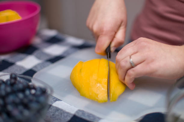 istock Young girl making fresh fruit salad, slicing mango 1407743400