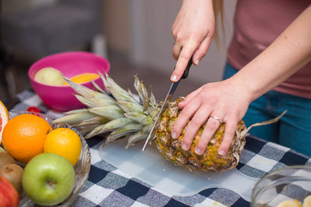 istock Young girl showing how to cut pineapple 1407743417