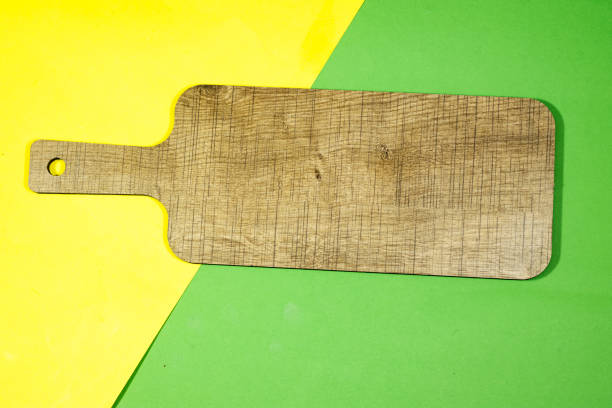 Wooden cutting board on a background of turquoise, yellow and pink colors