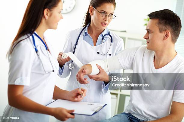 Man Having A Cast Put On His Arm By Two Female Medical Staff Stock Photo - Download Image Now