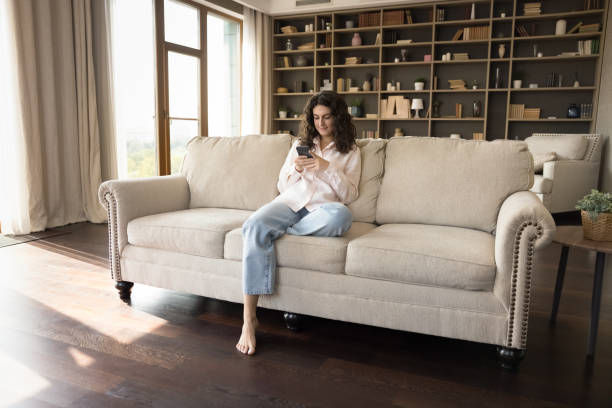 istock Pretty young millennial customer girl using smartphone on home couch 1407748437