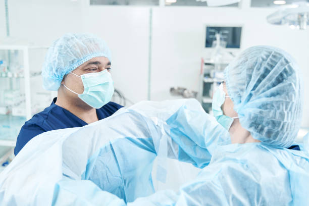 istock Two medical workers putting on their uniform for operation 1407750395