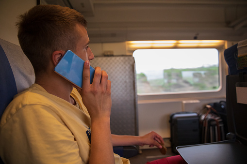 Teenager boy using a cellphone on a train