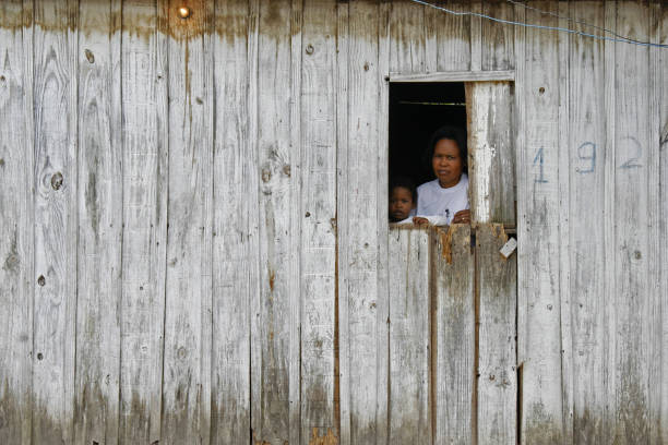 A mother and her son looking through the window of their house in the poor village Unidao, Porto Alegre Porto Alegre, Rio Grande do Sul, Brazil, Dec 08th, 2011: A mother and her son looking through the window of their house in the poor village Unidao family mother poverty sadness stock pictures, royalty-free photos & images