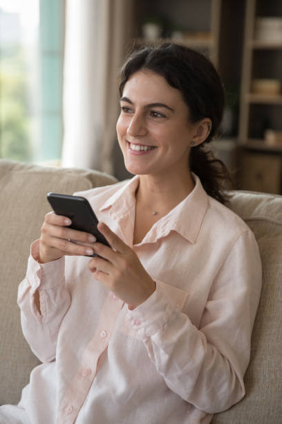 istock Happy cheerful cellphone user girl sitting on home sofa 1407759012